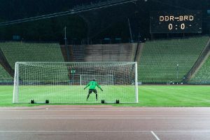 A goalkeeper in a goal in front of an empty stadium