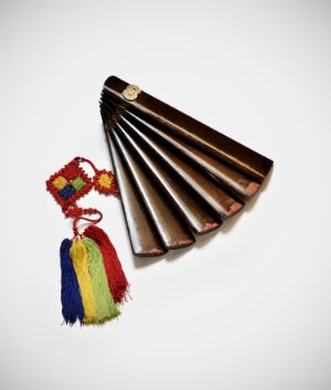 A kind of fan made of wood with colourful tassels attached.