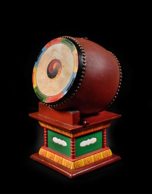 A drum with a brightly painted drumhead on a plinth.