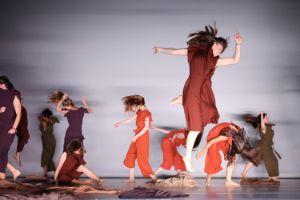 Ten dancers wear costumes in autumn tones and are carried by their movement.