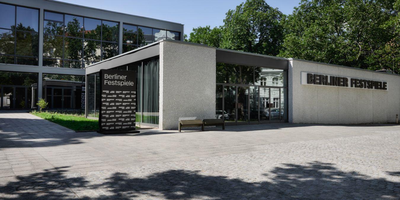 Außenansicht des Gebäudes der Berliner Festspiele mit modernem Eingangsbereich, großem Schriftzug und umgebenden Bäumen.