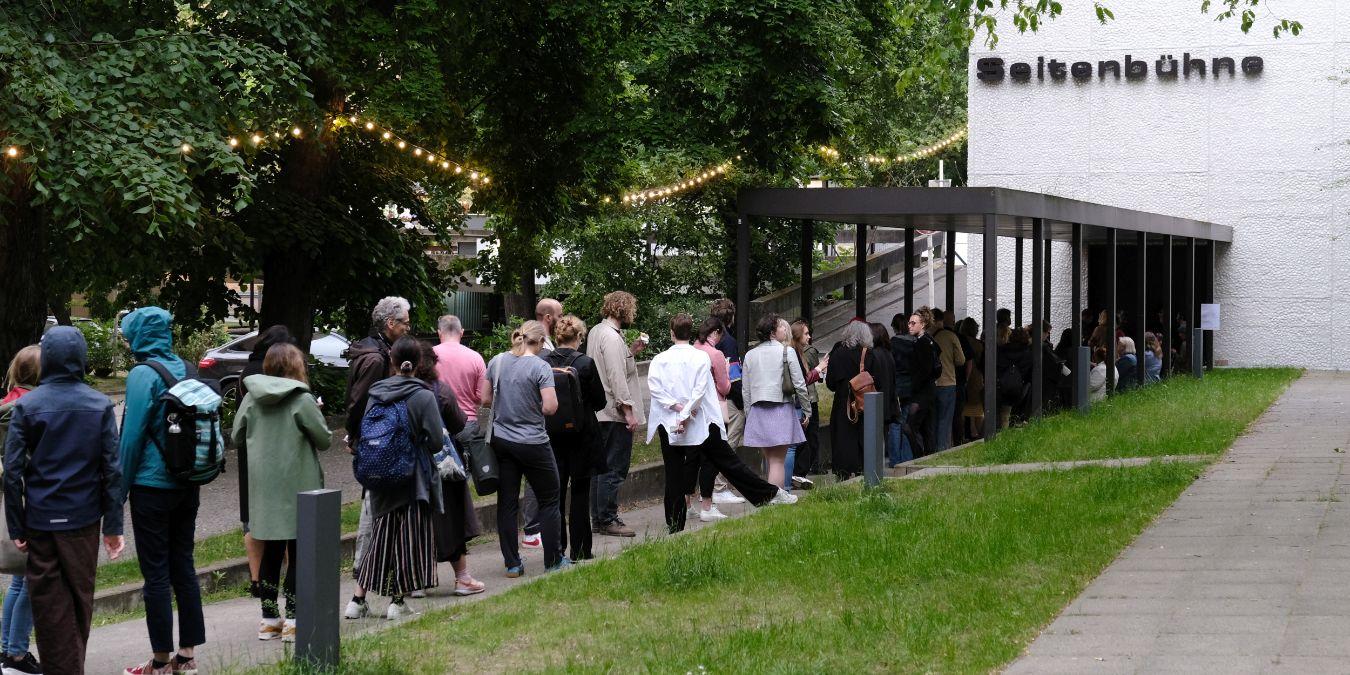 A line of people is queuing in front of the entrance to the side stage.
