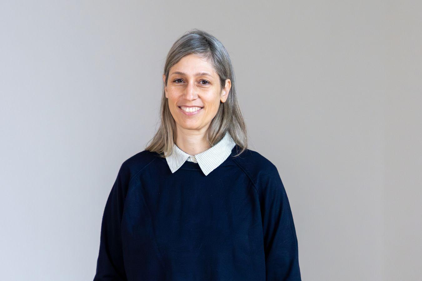 Porträt von Patrizia Dander. Sie lächelt, trägt Jeans und einen Pullover.