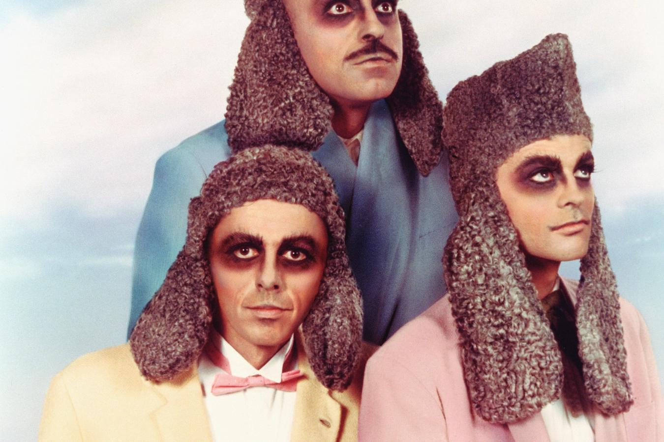 3 persons with dark make-up around the eyes, who wear caps with long earflaps