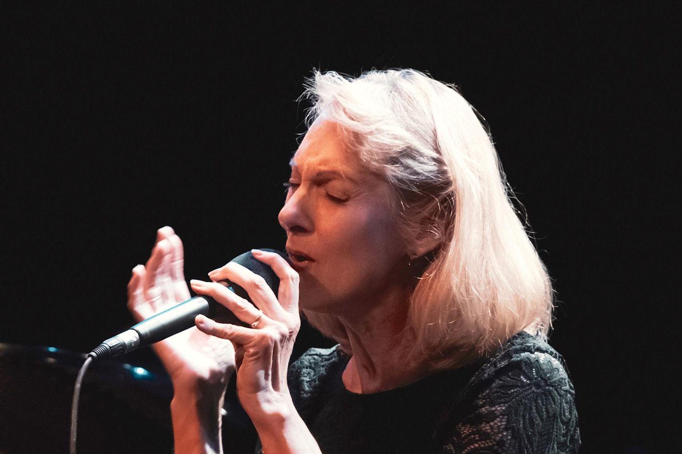 Lauren Newton sings dedicatedly into a microphone.