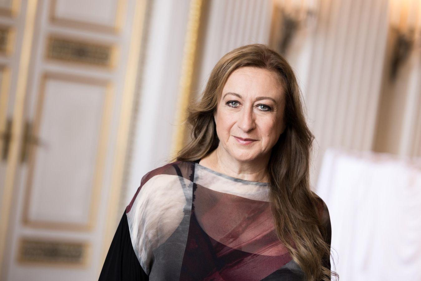 Eine Frau mit langen braunen Haaren geht auf die Kamera zu.