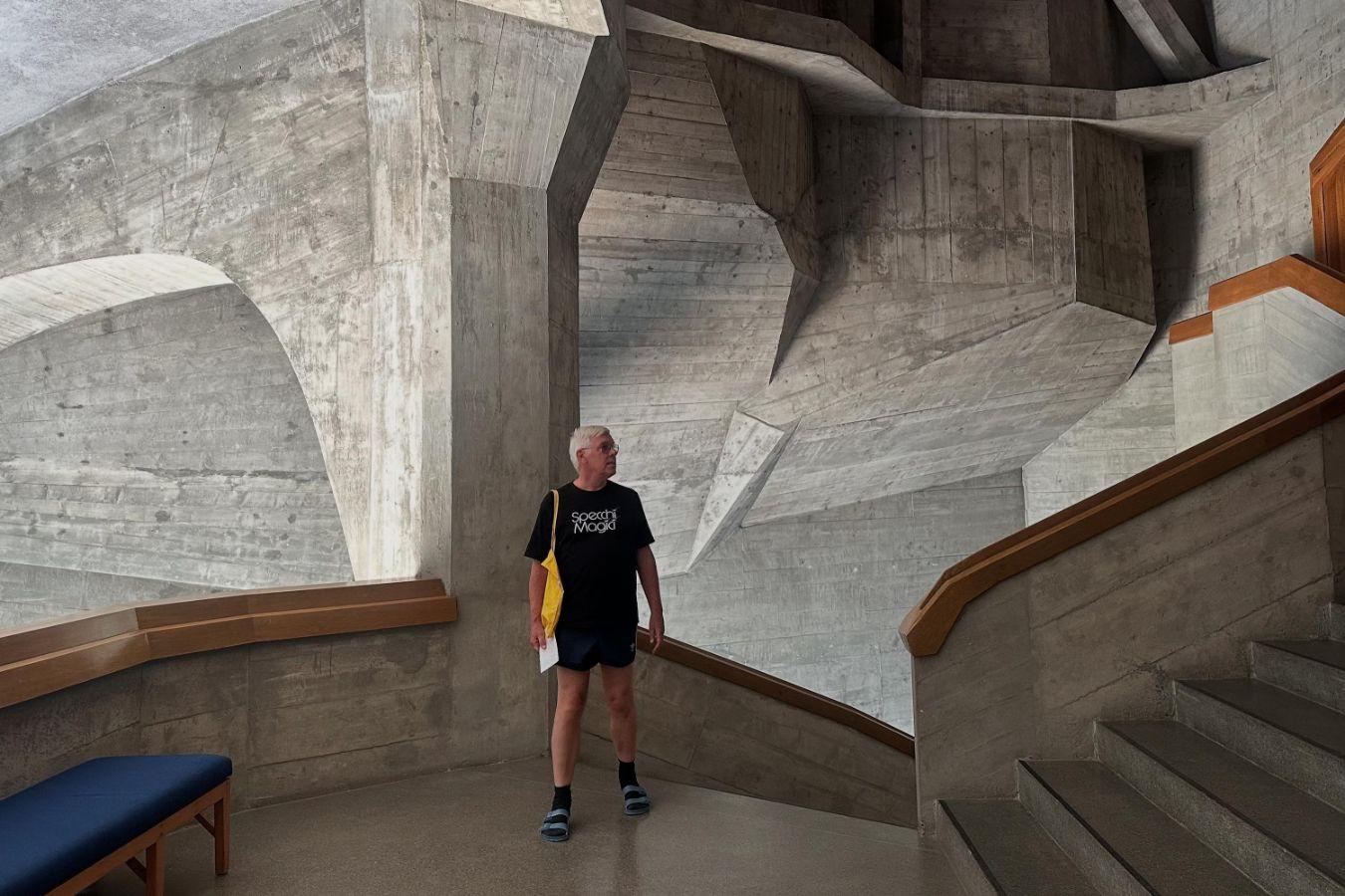 A person stands in an architecturally unusual building, looking around.