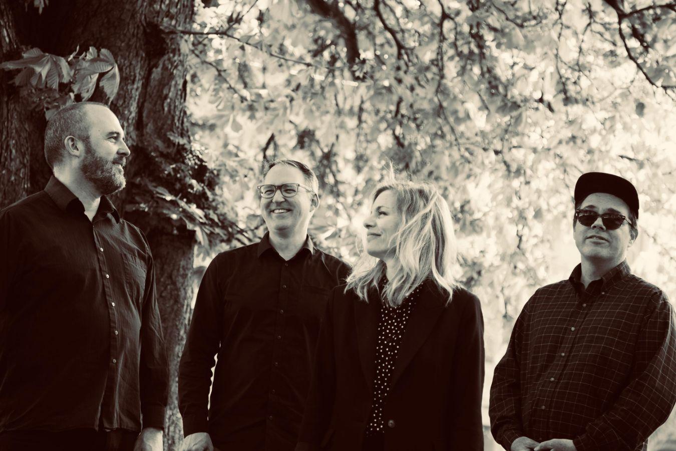 The band stand unter a tree, their faces joyful