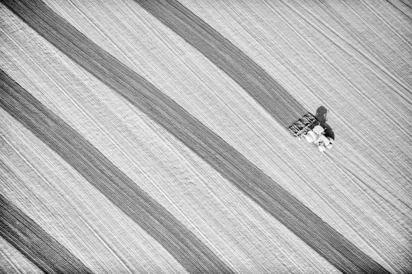 A tractor pulling a plow, view from above.