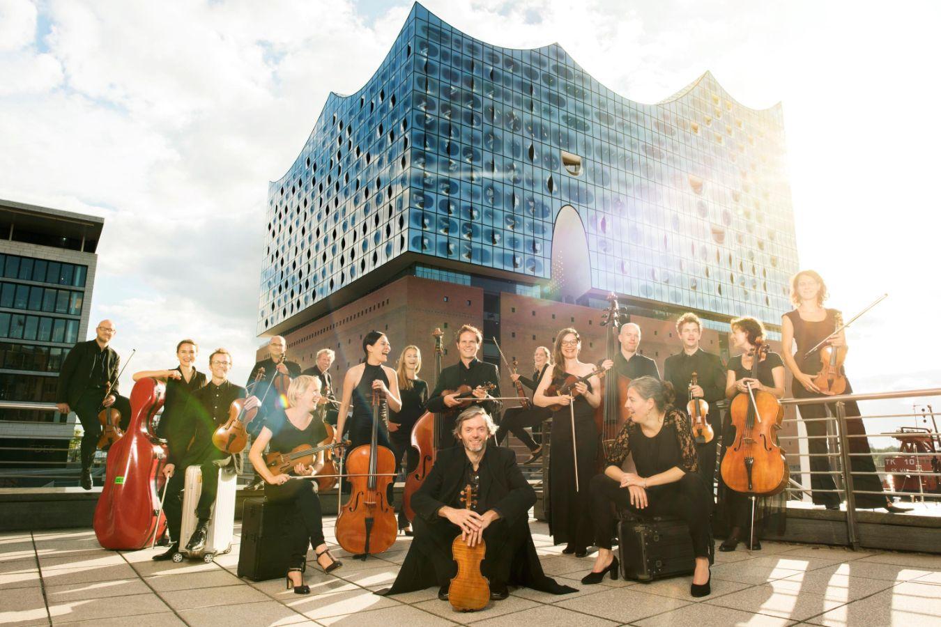 Mitglieder eines Orchesters stehen mit ihren Instrumenten vor der Elbphilharmonie in Hamburg.