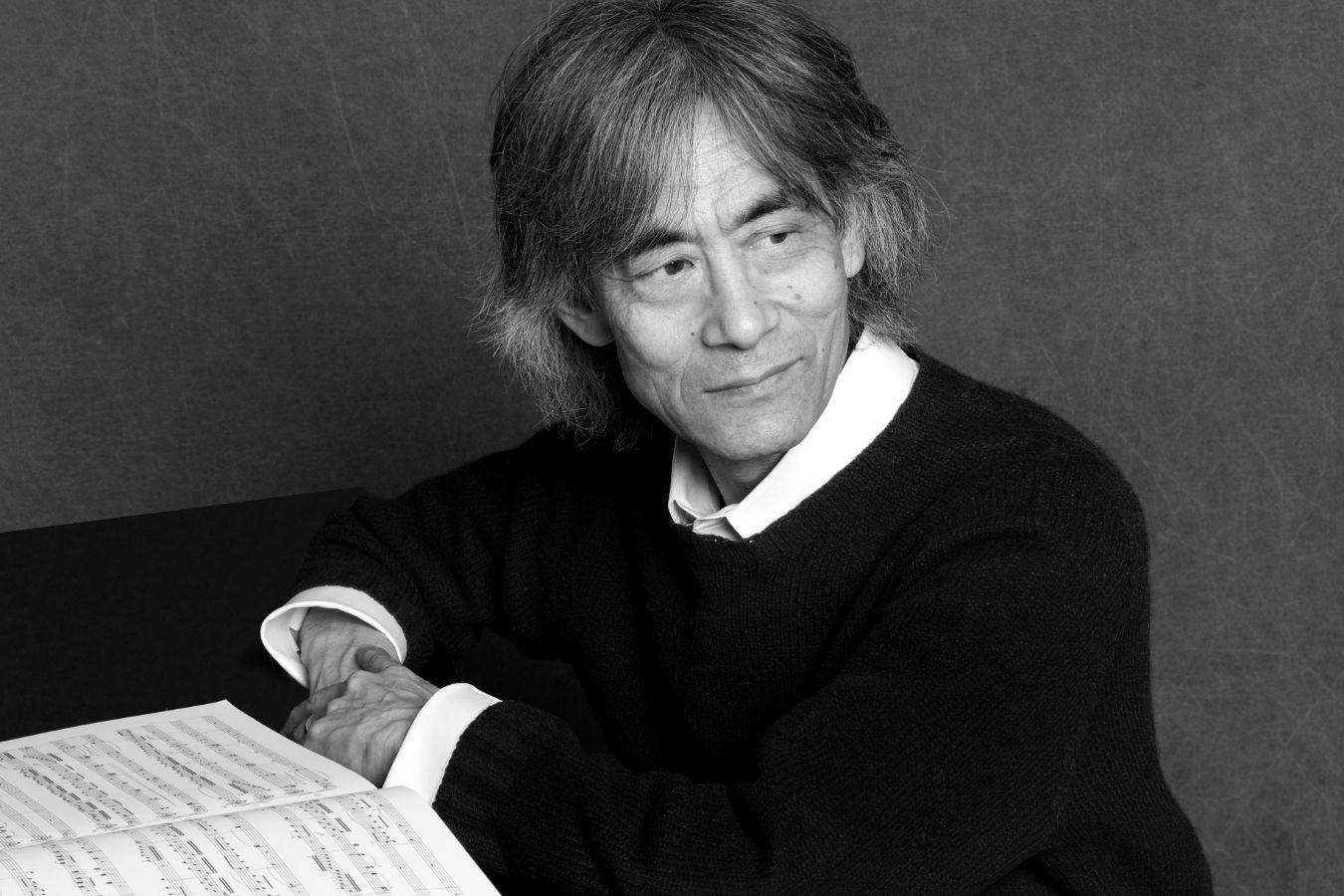 Ein älterer Mann mit grauen Haaren sitzt vor einer aufgeschlagenen Partitur und schaut nachdenklich an der Kamera vorbei.