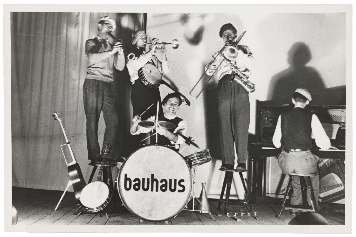 Four musicians play around a drum with Bauhaus written on it.