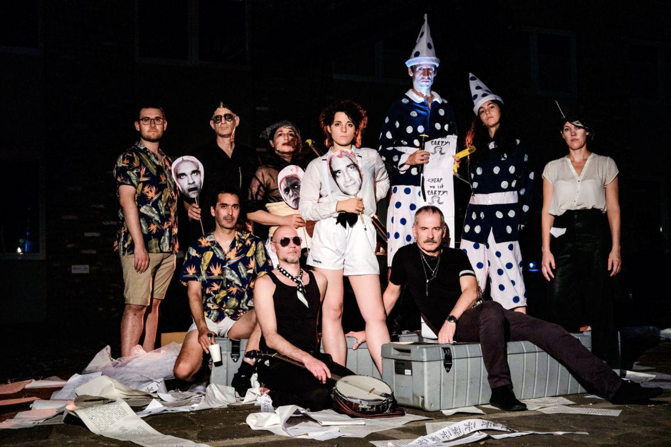 Ein Gruppenfoto von zehn Personen, die vor einem schwarzen Hintergrund stehen und sitzen.