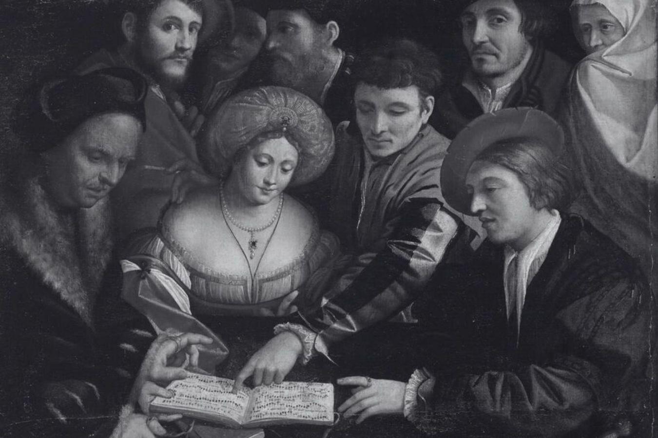 Several people stand around a woman and look at the sheet music of a piece of music together.