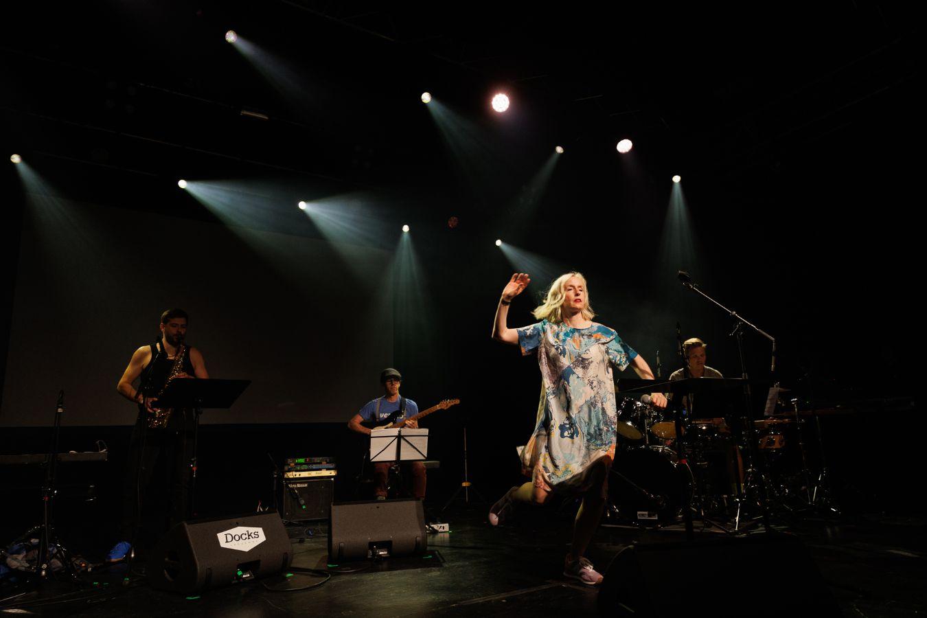 Jennifer Walshe performt auf der Bühne, im Hintergrund drei Musiker von Nikel