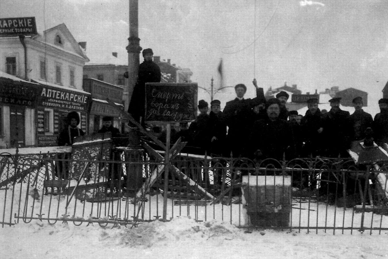 A crowd stands behind barricades on a snow-covered street.