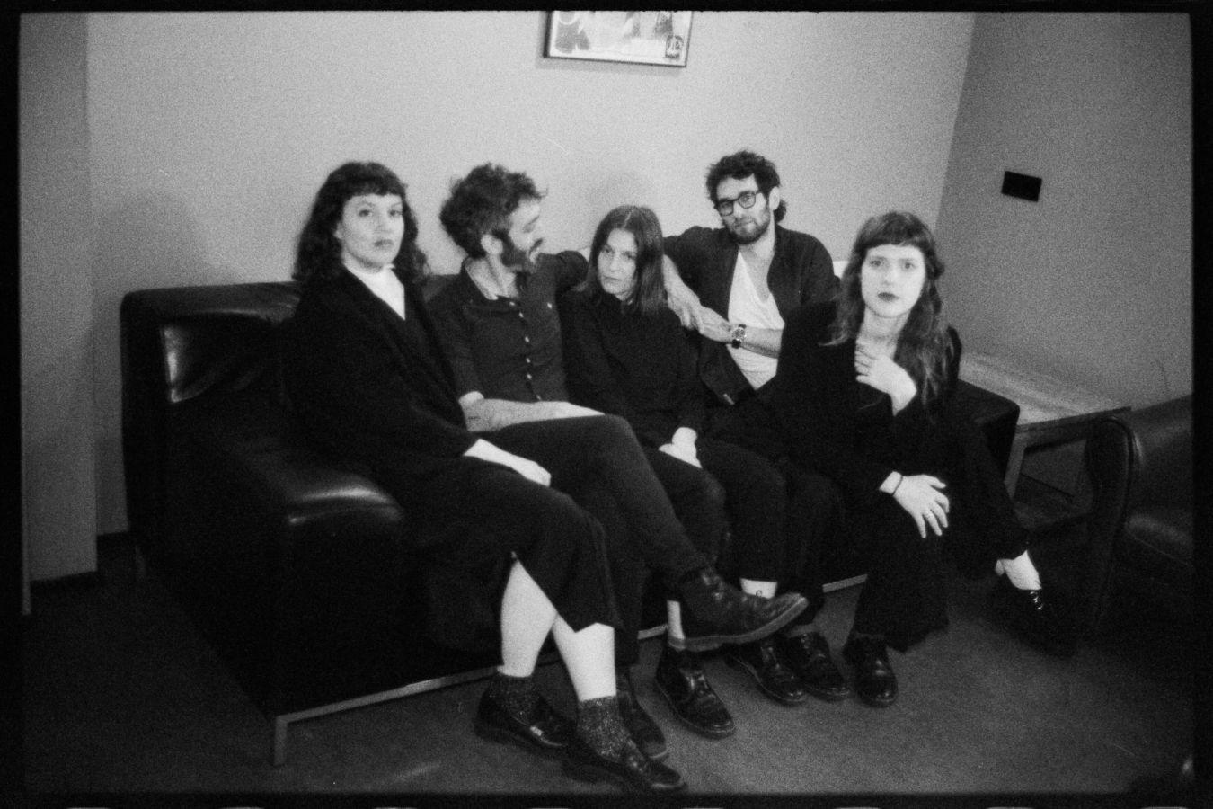 A black and white photo of five people sitting on a sofa.