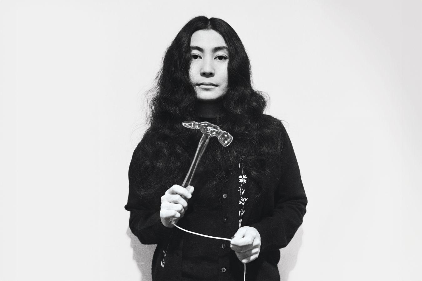 Schwarz-Weiß-Portrait von Yoko Ono, die ihr Werk "Glass Hammer" hält während der Ausstellung "HALF-A-WIND SHOW" bei der Lisson Gallery, London, 1967.