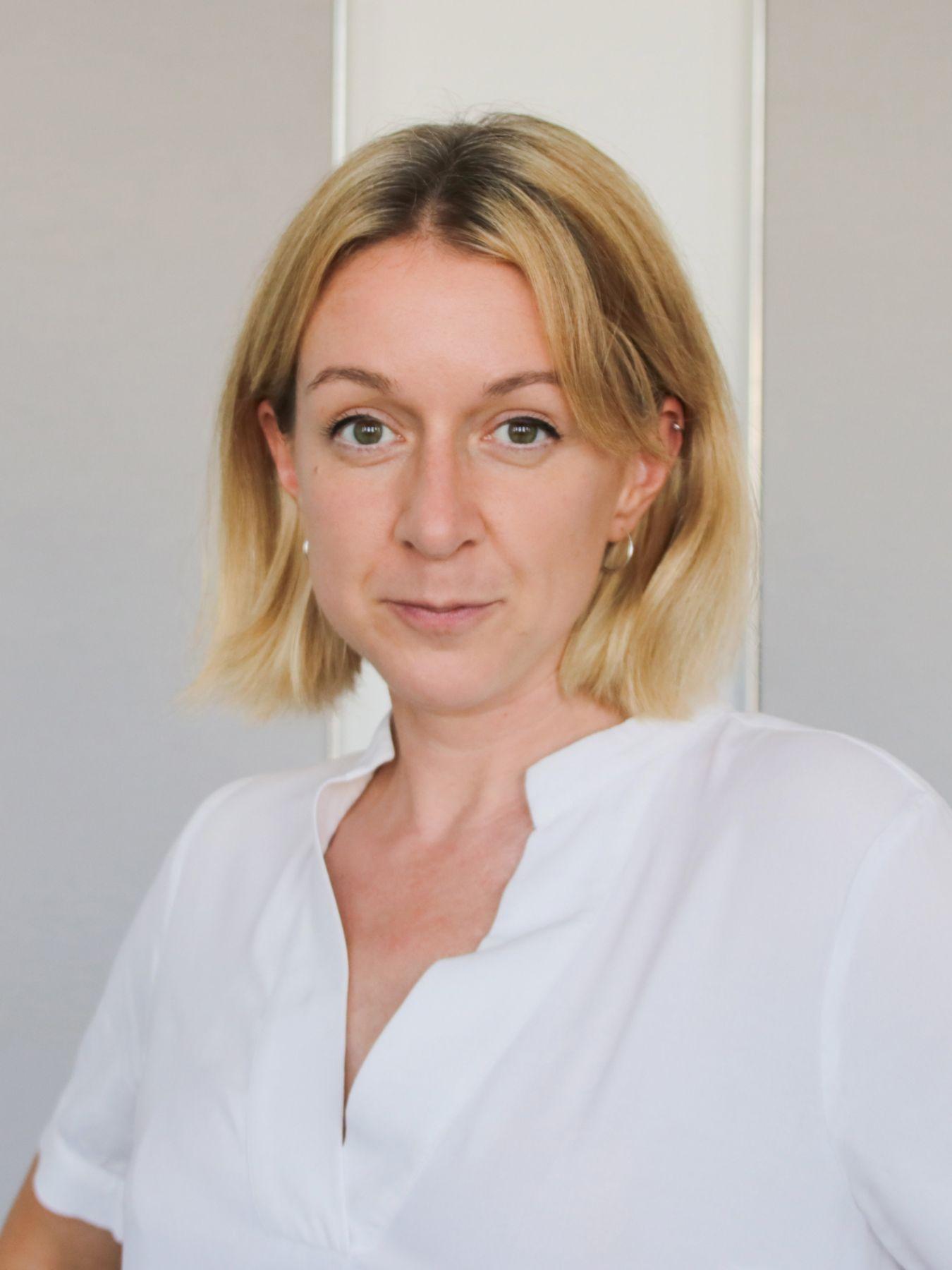 Porträt einer Frau mit langen blonden Haaren, die eine weiße Bluse trägt