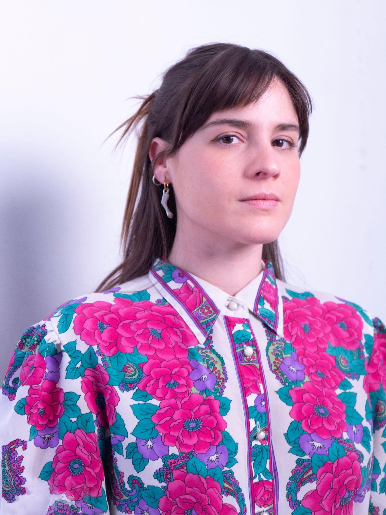 A woman with her hair pinned up wearing a floral blouse