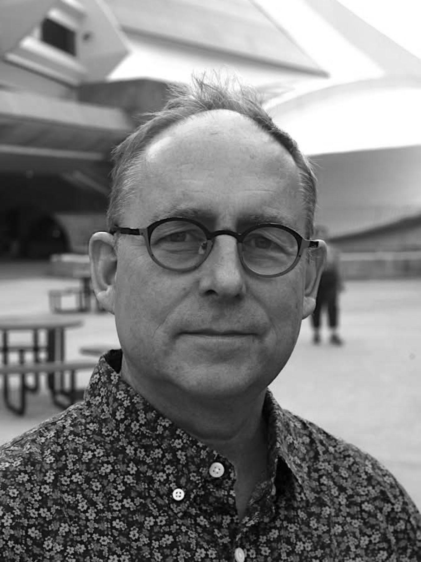 Porträt von Garnet Willis mit runder Brille und einem Hemd mit floralem Muster