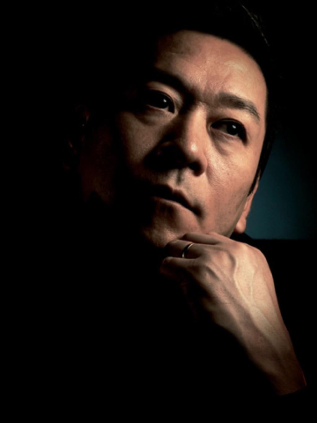 Portrait von Kohei Nawa im Halbdunklen: Nur Kohei Nawas Gesicht, das er in die Hand stützt, ist belichtet.