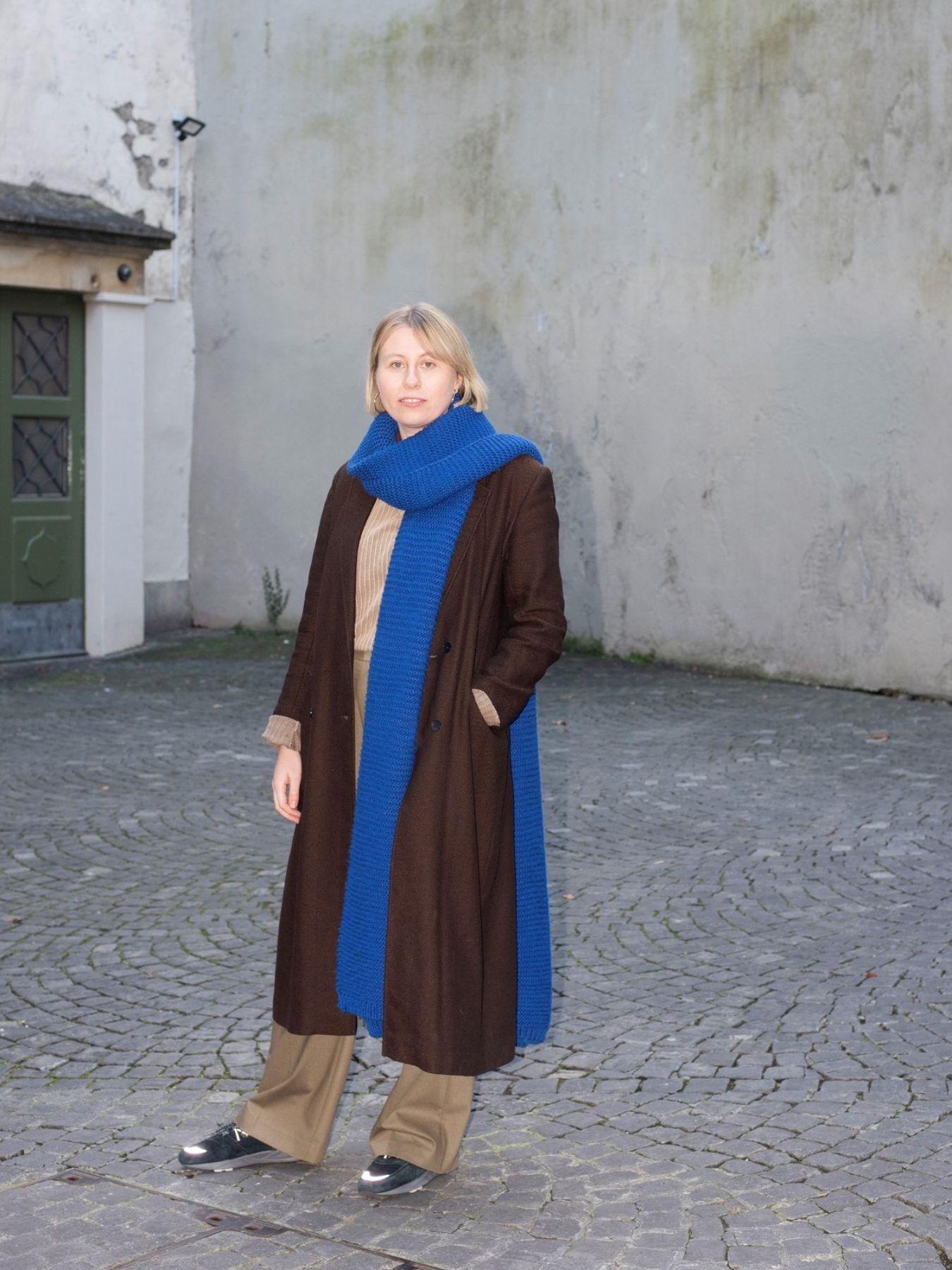 Woman in a brown coat and blue scarf