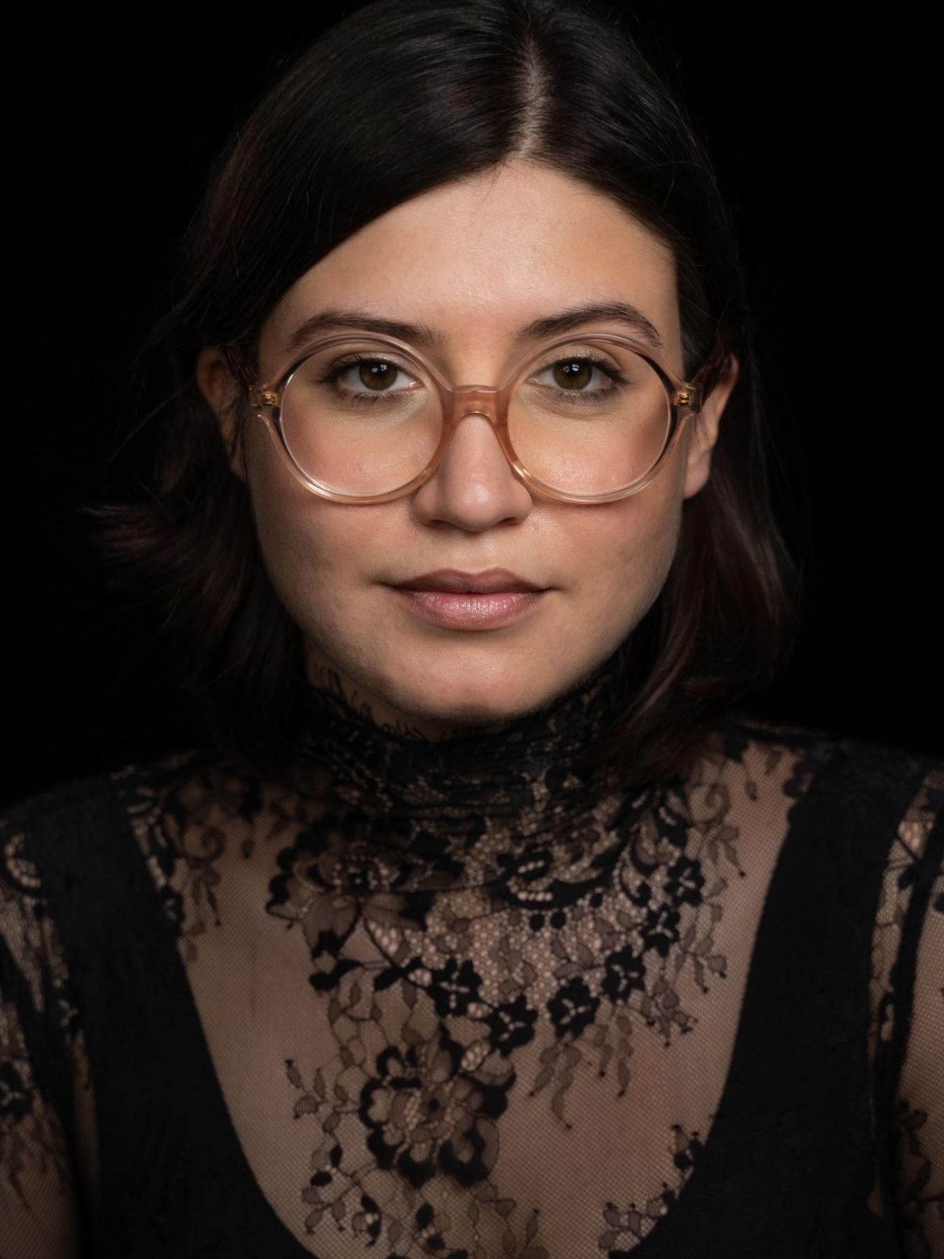 A woman with dark hair and large round glasses