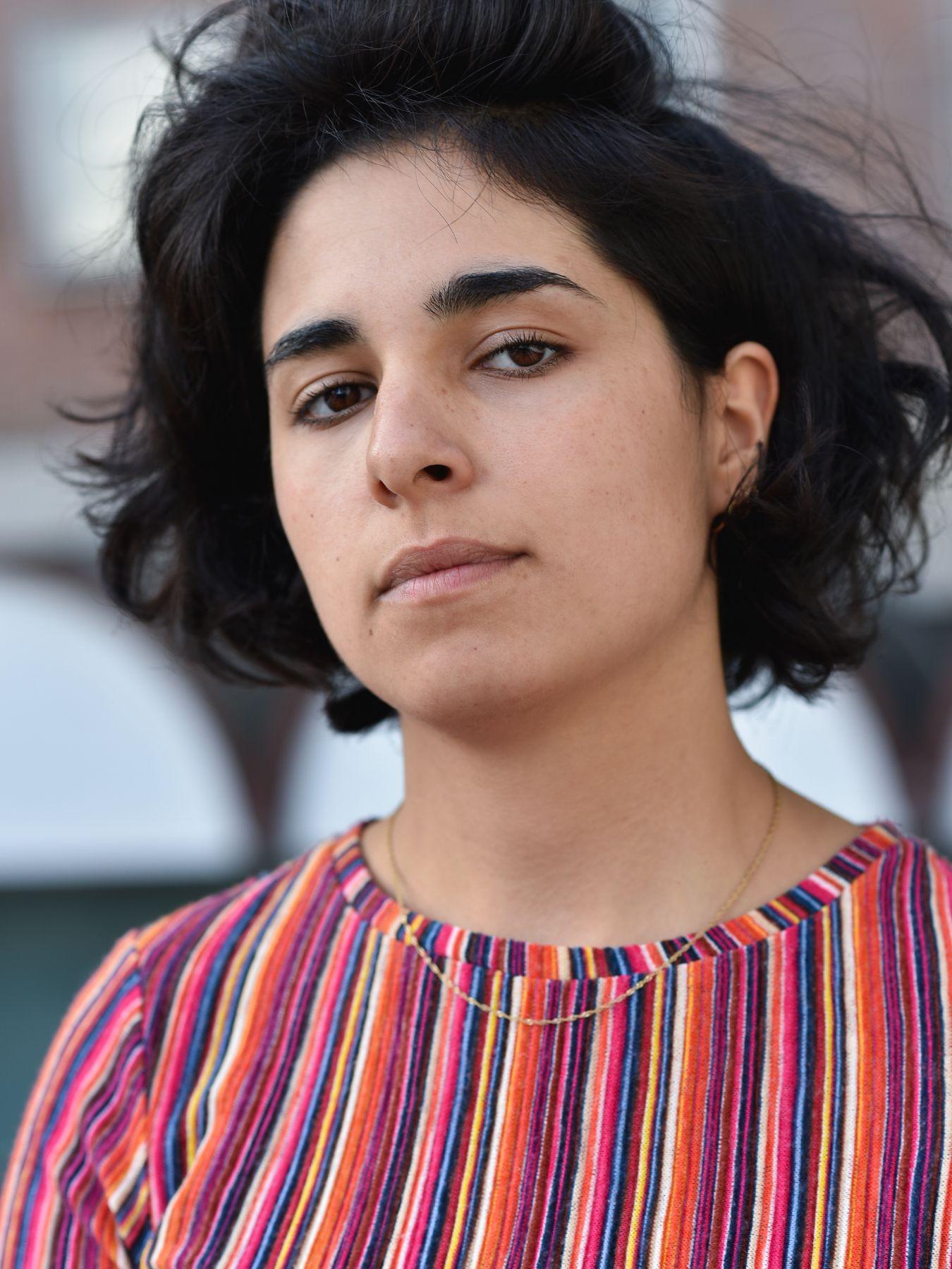 A woman with short dark-brown hair wearing a colourful striped top