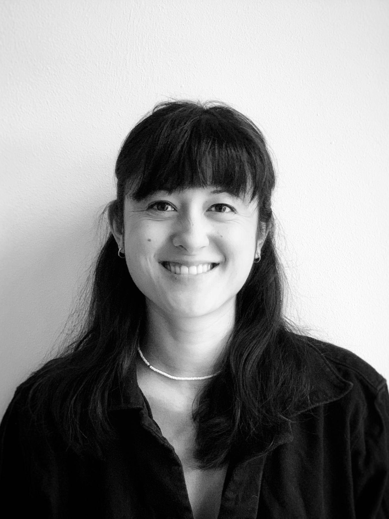 Black and white portrait of a woman in front of a white wall