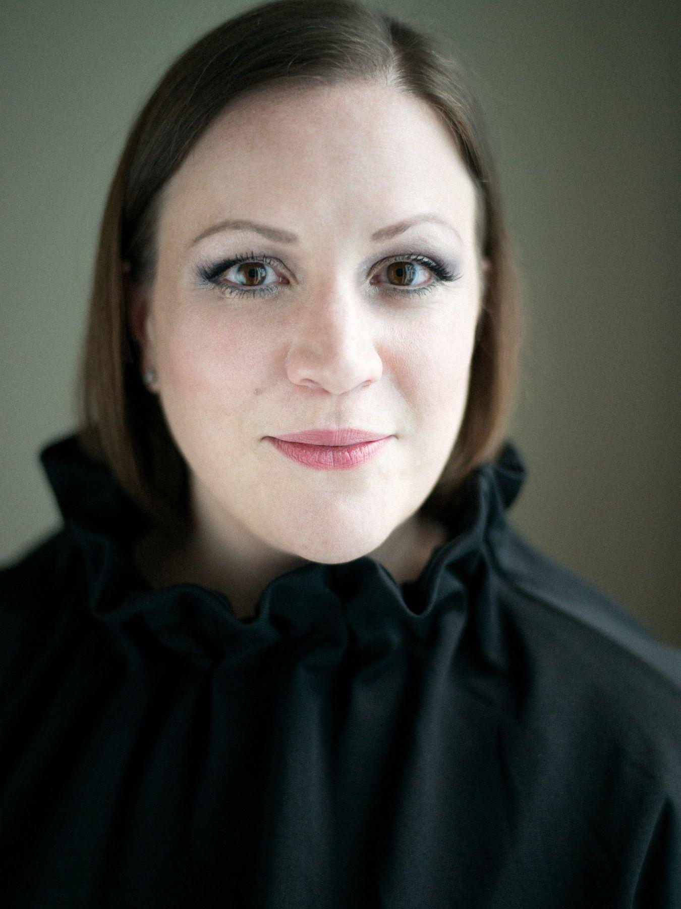 A woman with straight brown hair smiles at the camera.