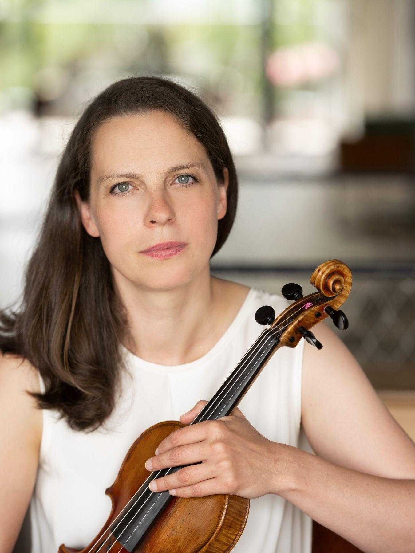 Gartemanns Blick ist ernst. Sie hält eine Geige vor sich.