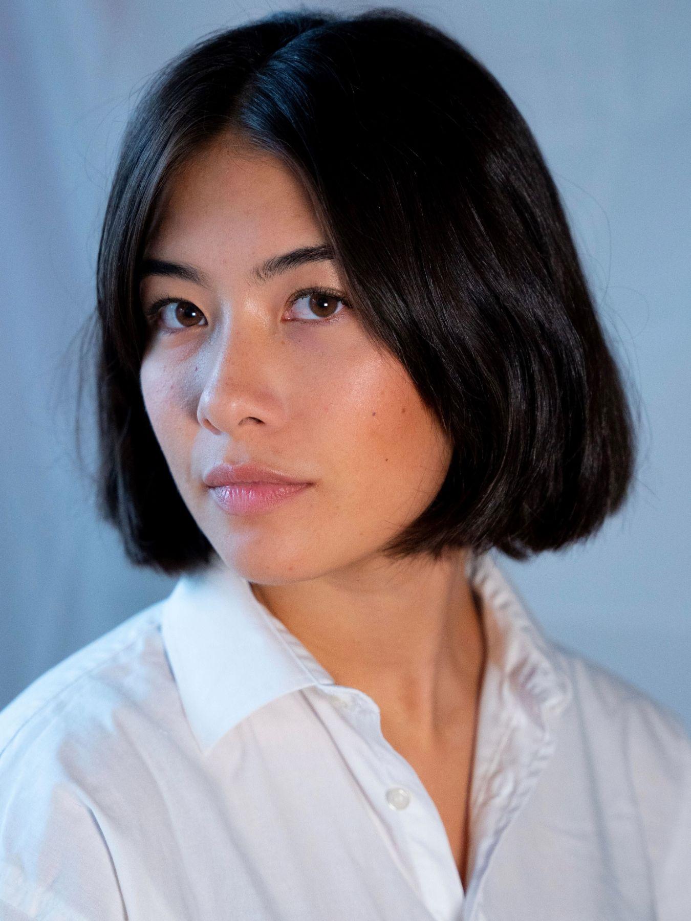 Portrait of a young women in front of a grey-blueish background.