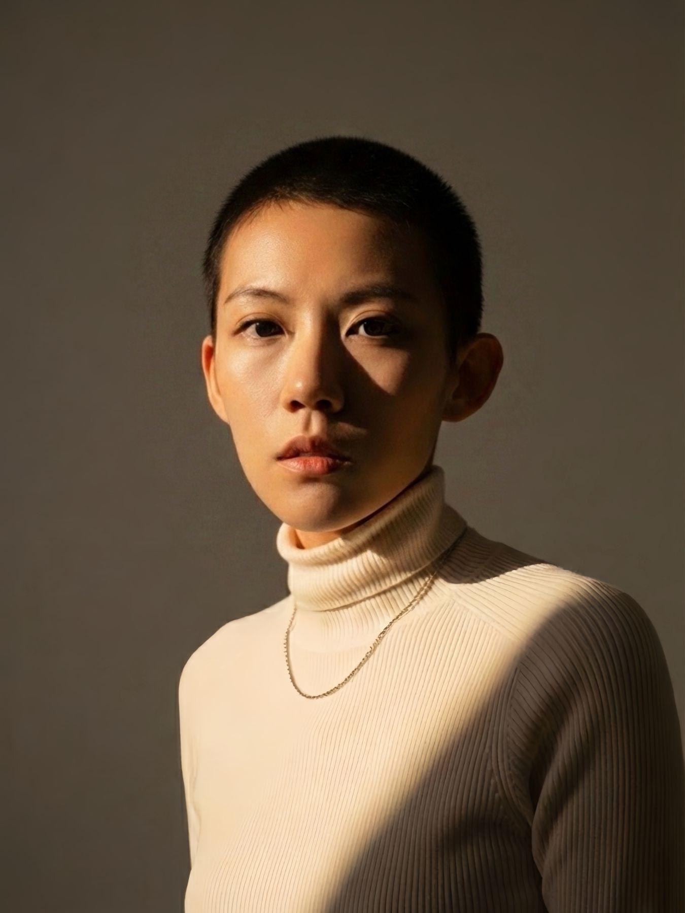 A woman with short dark-brown hair wearing a white turtleneck