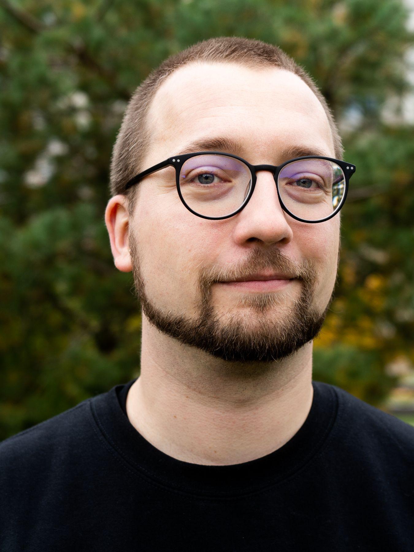 A man with short brown hair, a beard and glasses