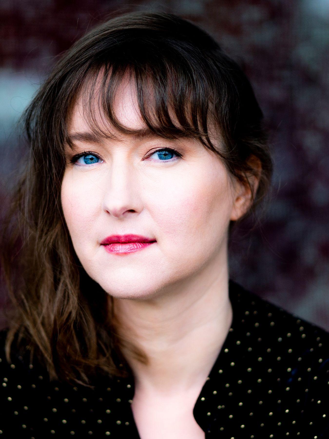 A woman looks seriously into the camera.