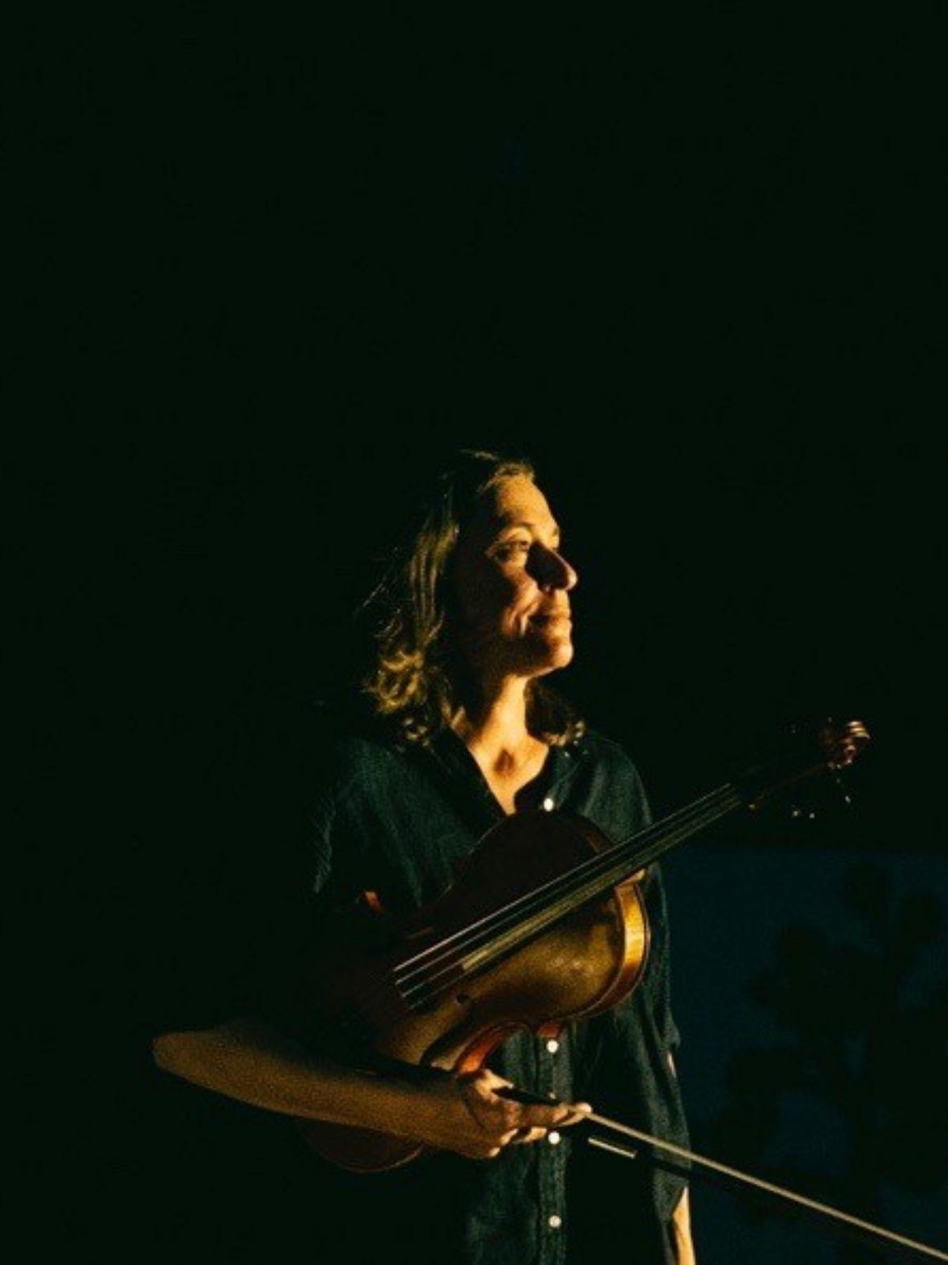 A woman with a viola in front of a black background.