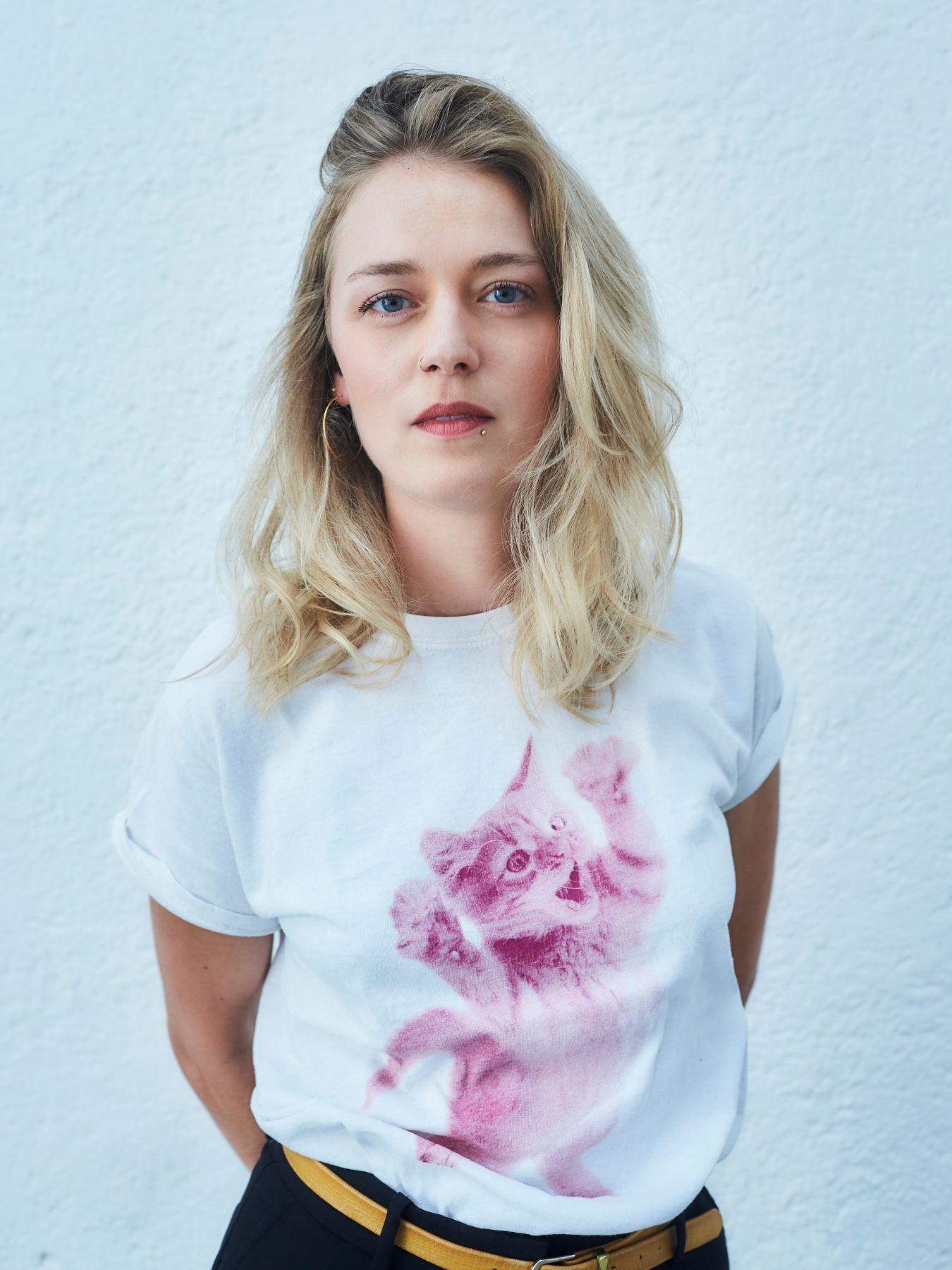 A blond person wearing a white t-shirt with a cat print