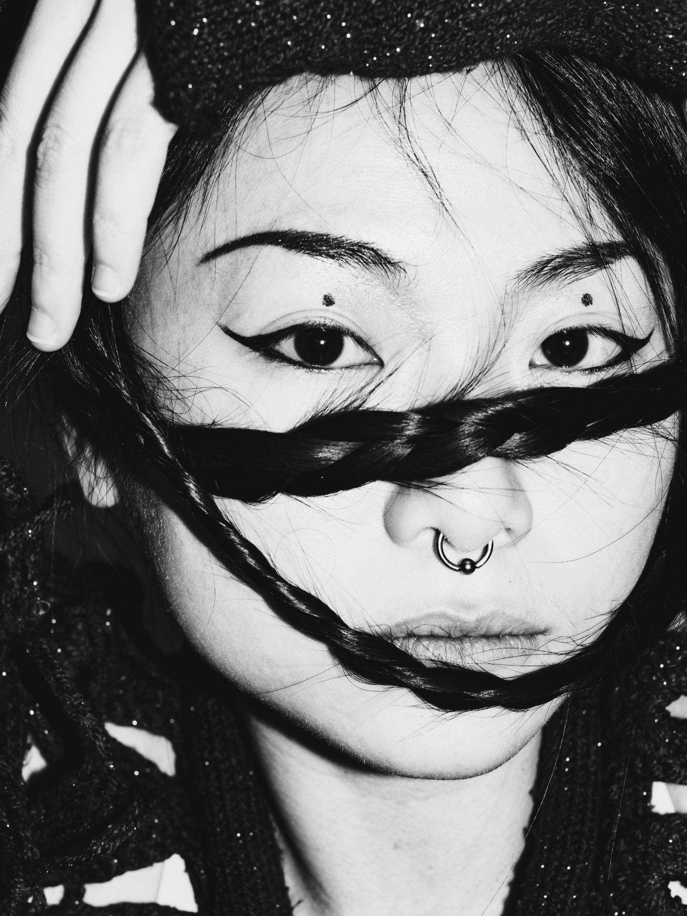 Otay:onii holds two plaited pigtails in front of her serious looking face.