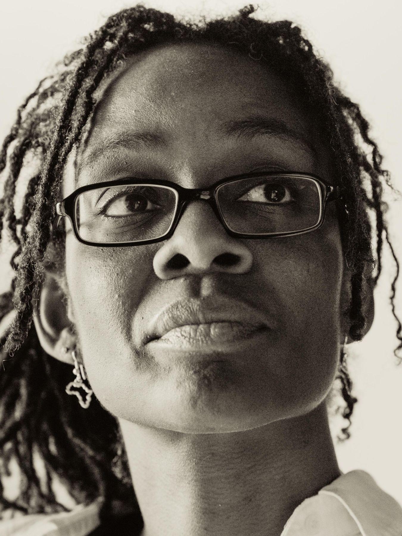 Eine schwarze Frau mit Brille und einem Ohrring.