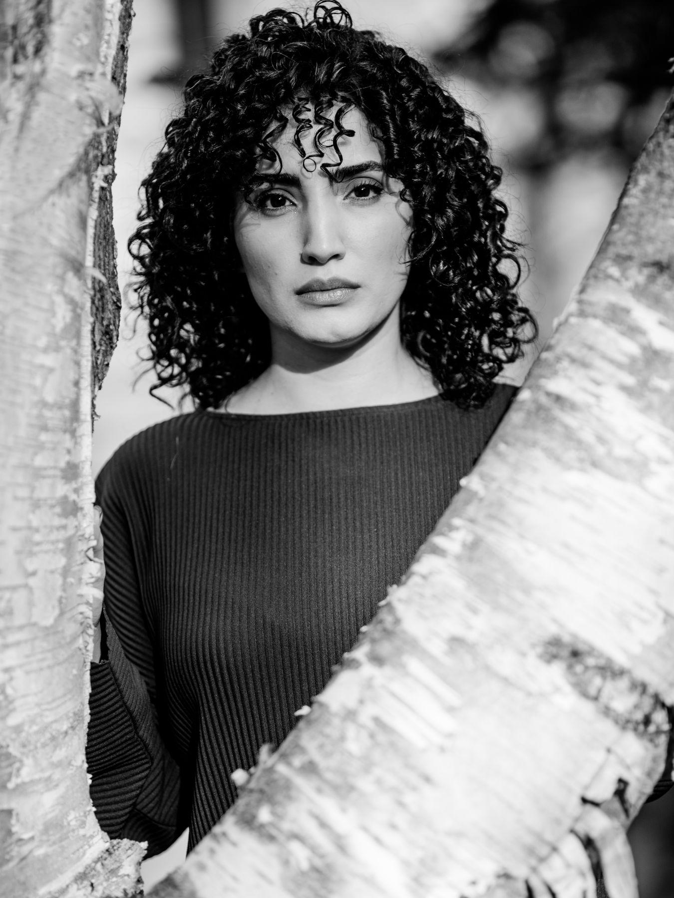 A woman with dark curly hair wearing a dark top