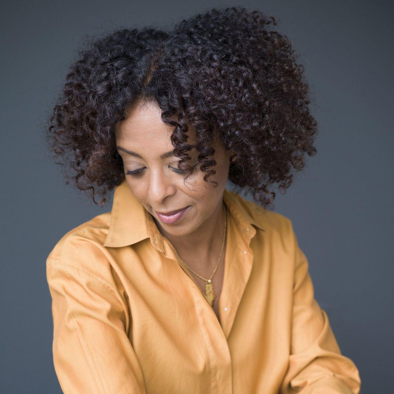 Maaza Mengiste is sitting with her head tilted down