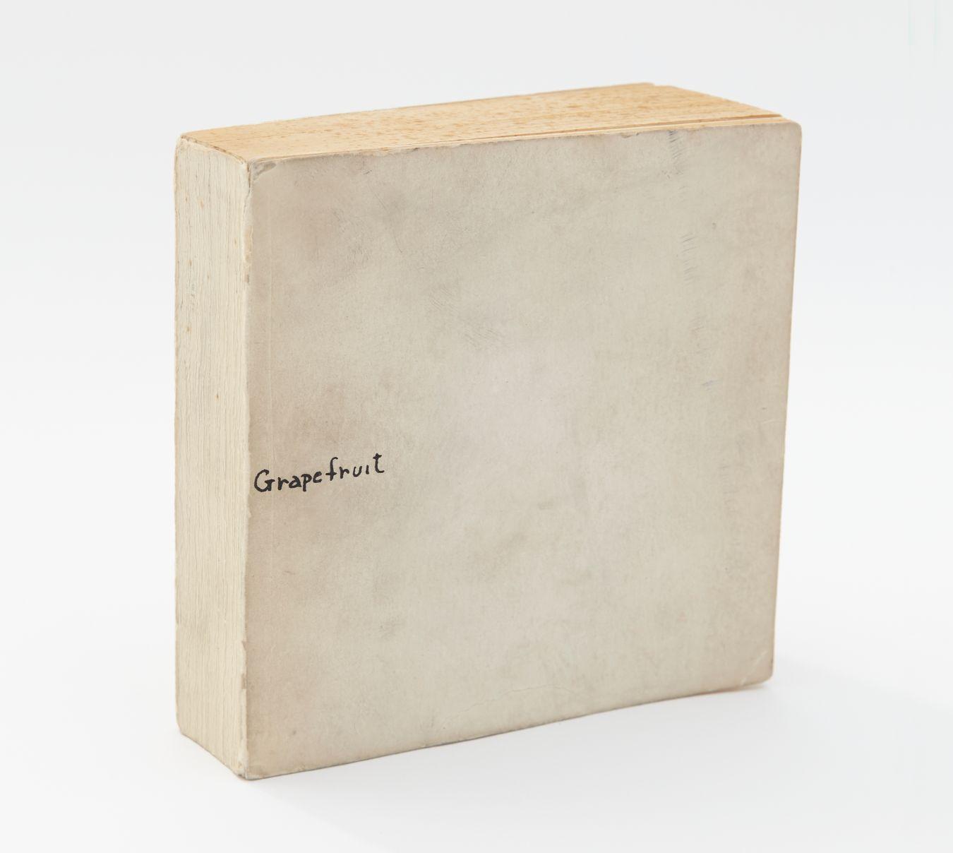 A photo of a white-yellowed book with the word "Grapefruit" written in small black letters on the cover.