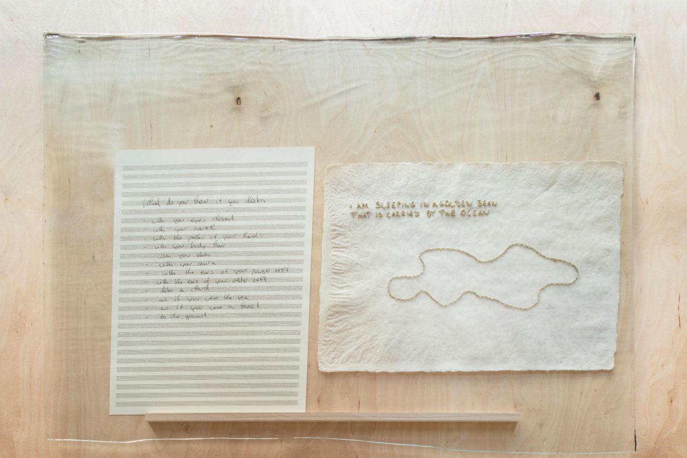 Zwei Papierblätter nebeneinander in einem Rahmen. Linkes Blatt mit diagonalen Streifen und Text. Rechtes Blatt mit Prägemuster und Text.
