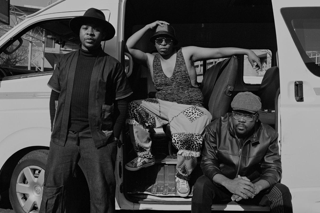 Musiker*innen aus dem Ensemble „The Brother Moves on“, die vor einem Kleinbus posieren.