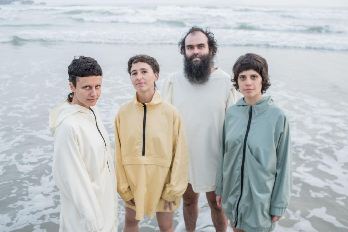 Quartabê members Mariá Portugal, Joana Queiroz, Maria Beraldo and Chicão stand at the water’s edge by the sea.