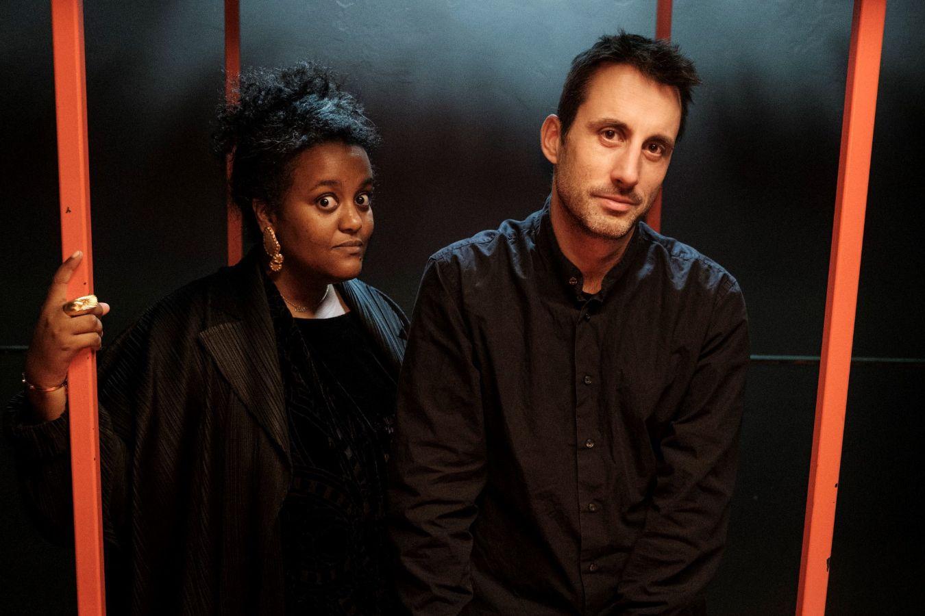 Ein Mann und eine Frau stehen zwischen zwei orangefarbenen Stäben.