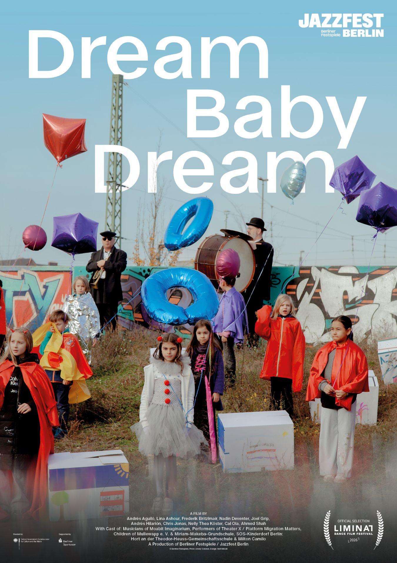 Group in colourful costumes stands on a grassy area with graffiti walls and balloons.