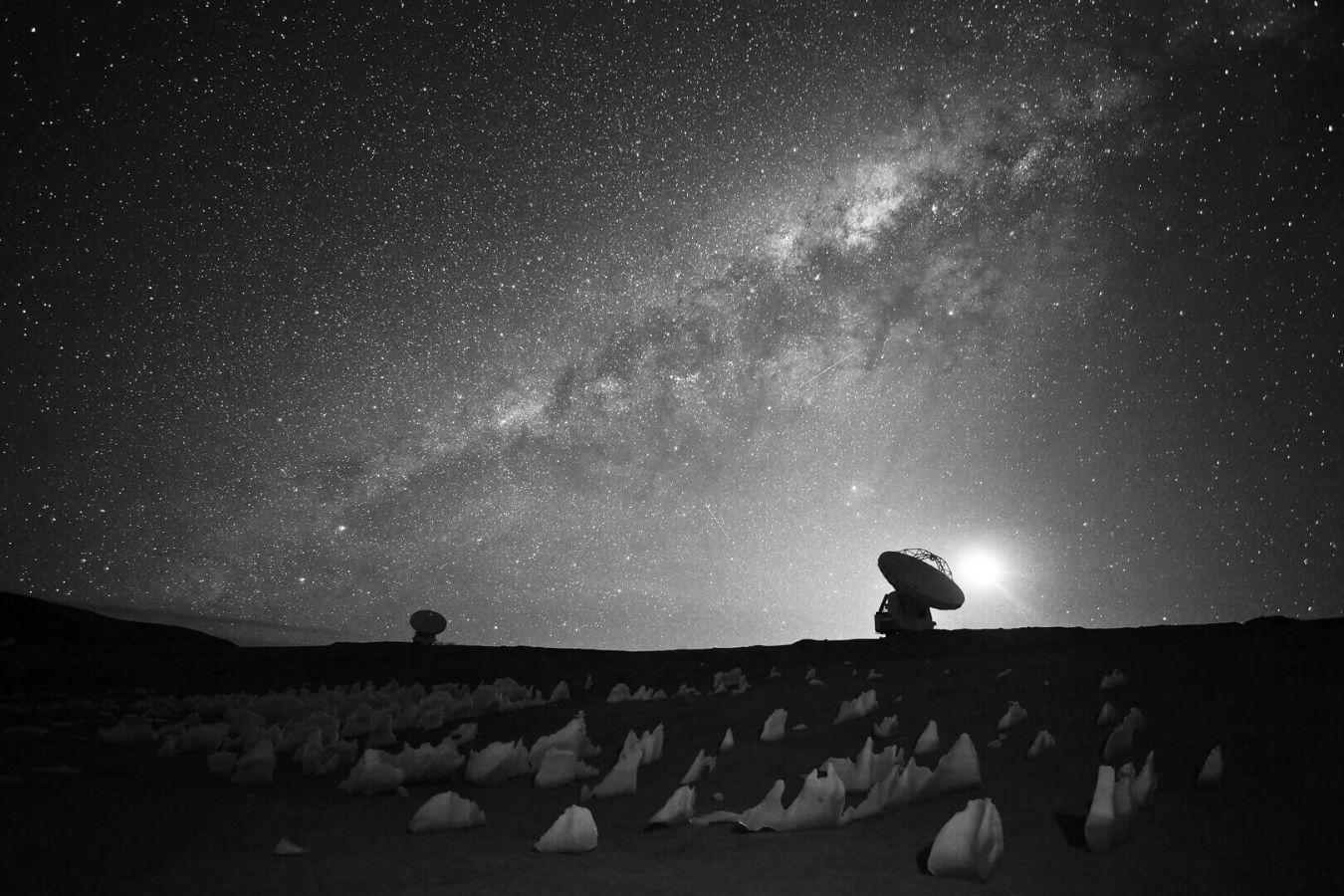 Zwei Teleskope in bergiger Landschaft lauschen in den Himmel