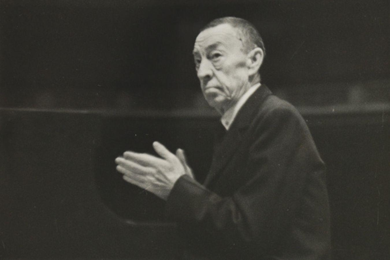 Ein Mann blickt aus dem Bild und hält die Hände vor der Brust